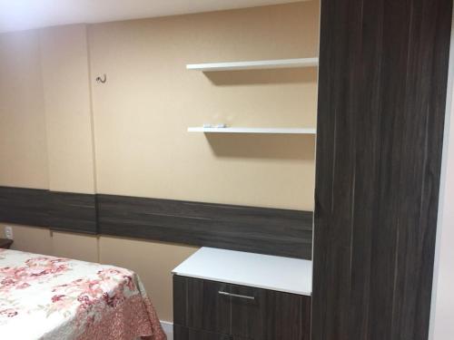 a bedroom with a bed and a desk and shelves at Apart Porto das Dunas in Aquiraz