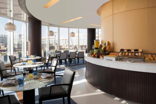 a dining room with tables and chairs and windows at Fraser Suites Riyadh in Riyadh