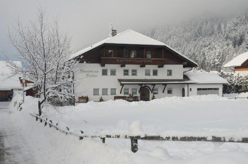 a snow covered building with a fence in front of it at Pension Pichler in Chienes