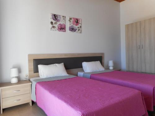 two beds in a room with pink sheets at Egrypos Hotel in Petrití