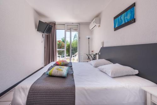 a bedroom with two beds and a tv on the wall at Le Clos des Bruyères in Vallon-Pont-dʼArc