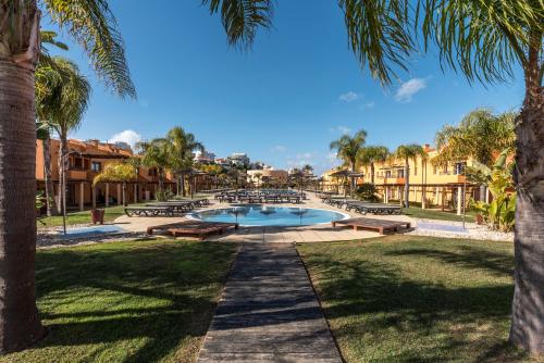 a swimming pool in a park with palm trees at Luxury Apartment, Marina, Beach & Pool in Portimão