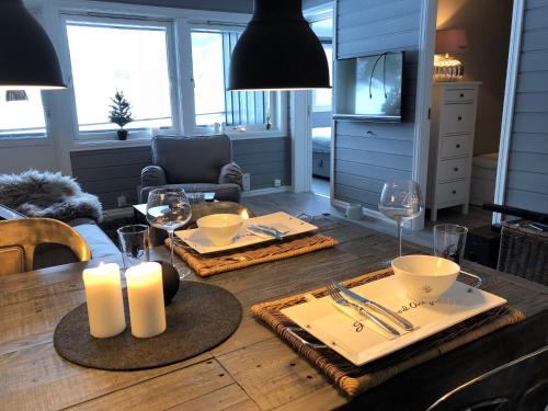 a dining room table with two white plates and candles at Storehorn Apartments in Hemsedal