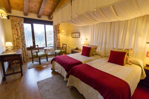 a bedroom with two beds and a desk and window at Hotel Llano Tineo in Villanueva de la Vera