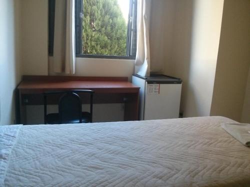 a bedroom with a bed and a desk and a window at Bekassin Botucatu Hotéis Ltda in Botucatu