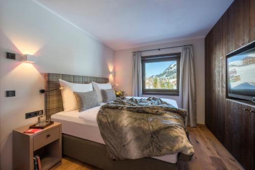 a bedroom with a bed and a window and a television at Nidus Luxury Apartments in Lech am Arlberg