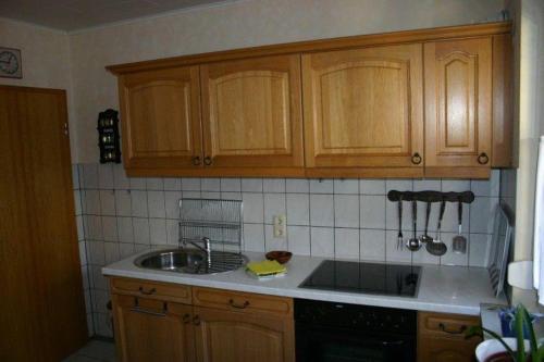 a kitchen with wooden cabinets and a sink at Haus-Kummeleck-Wohnung-3 in Bad Lauterberg