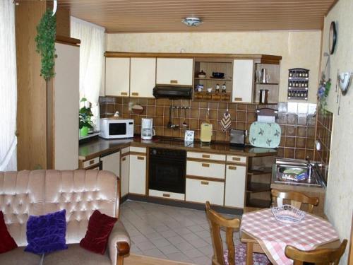 een keuken met witte kasten en een tafel en een tafel bij Haus-Kummeleck-Wohnung-4 in Bad Lauterberg