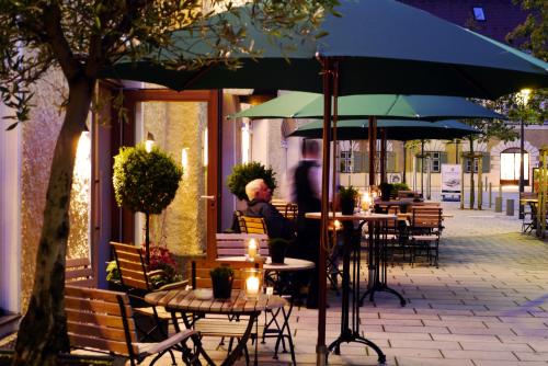 a man sitting at a table under an umbrella at Romantik Hotel Das Lindner in Bad Aibling