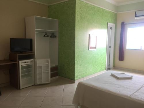 a bedroom with a bed and a tv and green walls at Hotel Mais in Macapá