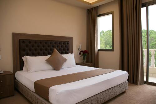 a bedroom with a large bed with a large window at Bzommar Palace Hotel in Harisa