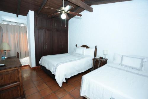 a bedroom with two beds and a ceiling fan at Hotel Casa Colonial Boutique in Managua