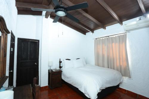 a bedroom with a white bed and a ceiling fan at Hotel Casa Colonial Boutique in Managua