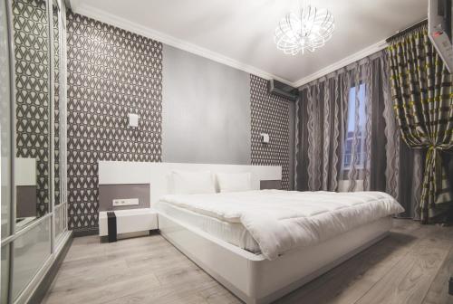a bedroom with a white bed and a chandelier at Kapitan Apartments in Odesa