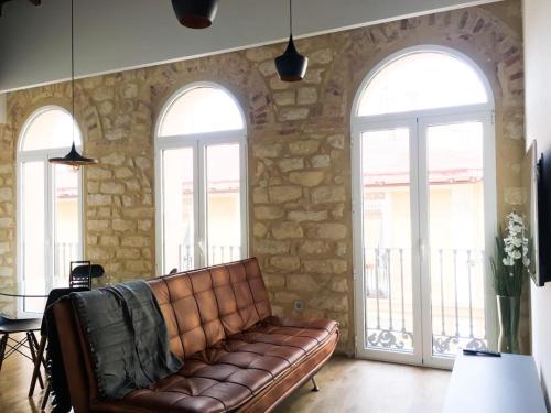 a leather couch in a room with three windows at Alicante old city & beach appartment in Alicante