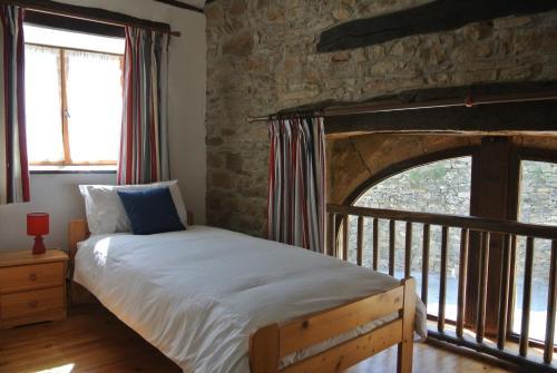 Broquiès的住宿－La Caze Gites，一间卧室设有一张床和石墙