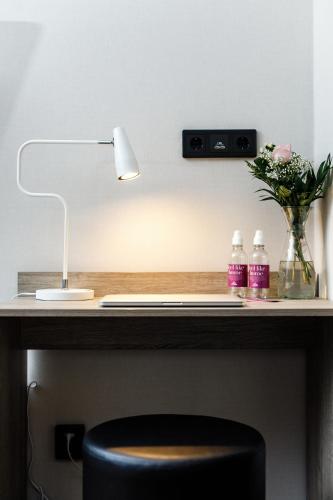 a desk with a lamp and a vase of flowers at Hotell Nissastigen in Gislaved
