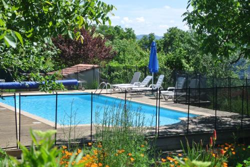 une piscine avec deux chaises et un parasol dans l'établissement La Caze Gites, à Broquiès