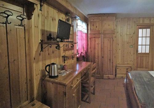 eine Küche mit Holzwänden, einem Tisch und einem TV in der Unterkunft Kleine in Gressoney-Saint-Jean