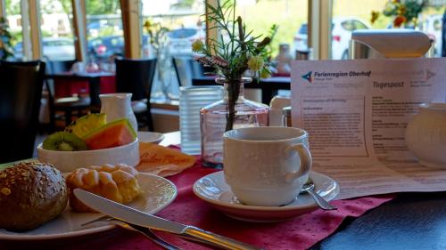 una mesa con una taza de café y un plato de fruta en Schlossberghotel Oberhof, en Oberhof