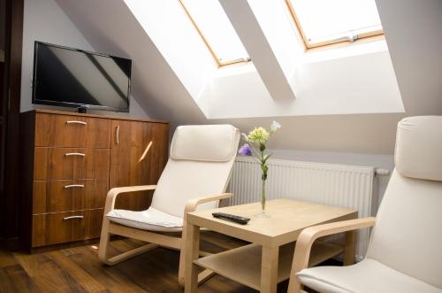 a living room with two chairs and a table and a tv at Villa Hof in Luboń