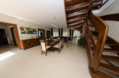 a dining room and living room with a wooden spiral staircase at Villa Hof in Luboń
