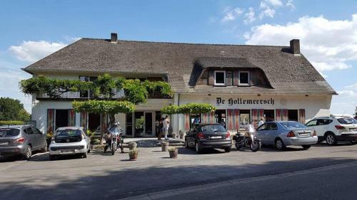 a building with cars parked in a parking lot at De Hollemeersch Hotel in Dranouter