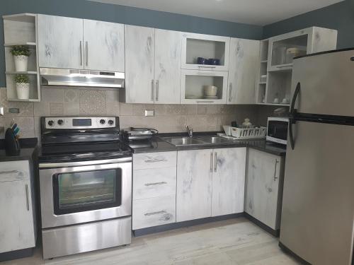 a kitchen with white cabinets and stainless steel appliances at Cadaques Caribe Pez 103 in Bayahibe