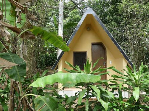 a small yellow house with a black roof at Chalés Sítio do Alemão in Ubajara