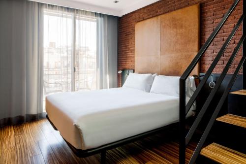 a white bed sitting in a bedroom next to a window at Hotel Granados 83, a Member of Design Hotels in Barcelona