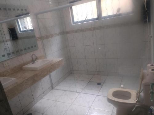 a white bathroom with a toilet and a sink at Casa de Campo Serra Negra in Serra Negra