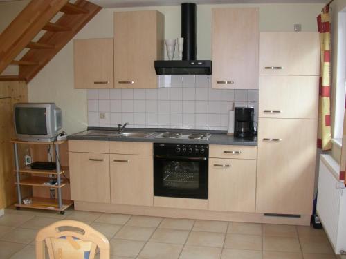 a kitchen with a stove and a sink and a refrigerator at Ferienwohnung Am Zechenhaus in Bodenmais