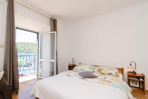 a bedroom with a white bed and a balcony at Apartments Linda in Polače
