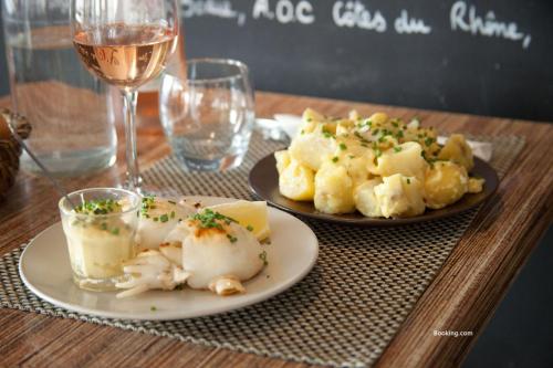 Una mesa con dos platos de comida y una copa de vino. en Hôtel Restaurant Gédéon, en Carnon-Plage