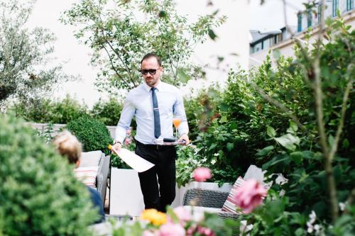 a man in a tie is walking through a garden at The Club Hotel & Spa Jersey in Saint Helier Jersey