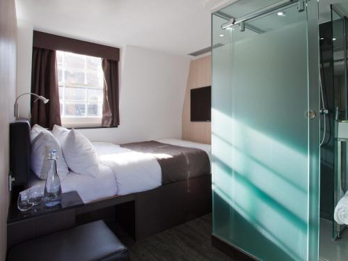 a hotel room with a bed and a glass shower at The Z Hotel Soho in London
