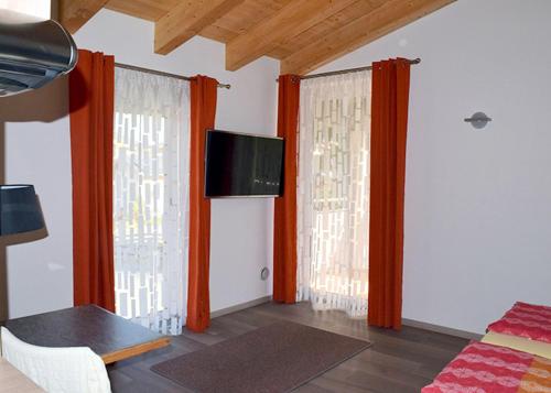 sala de estar con 2 ventanas con cortinas de color naranja en Flatscher‘s, en Niederau