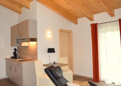 a living room with a couch and a table and a kitchen at Flatscher‘s in Niederau
