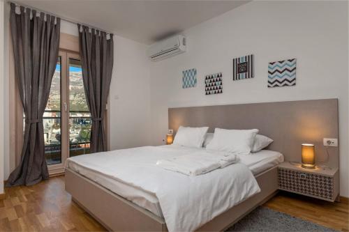 ein Schlafzimmer mit einem großen weißen Bett und einem Fenster in der Unterkunft Apartments Krug in Budva
