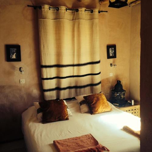 a bedroom with a bed with a curtain and two pillows at Maison d'Hôtes Irocha in Tisselday