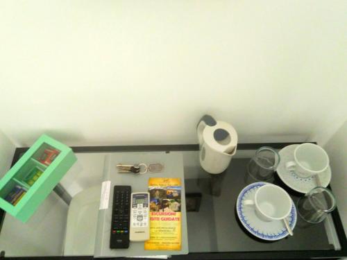 a shelf with a remote control and plates and cups at Il S'Ogno in Santa Teresa Gallura