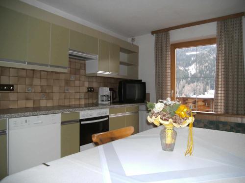 una cocina con una mesa con un jarrón de flores. en Apartments Jäger en Trins