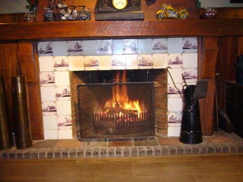 a fireplace in a living room with a fire at Hotel-Eetcafé d'Olde Heerd in Balkbrug