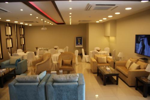 una sala d'attesa con divani, tavoli e TV di Al Mokhmalia Residential Units a Medina