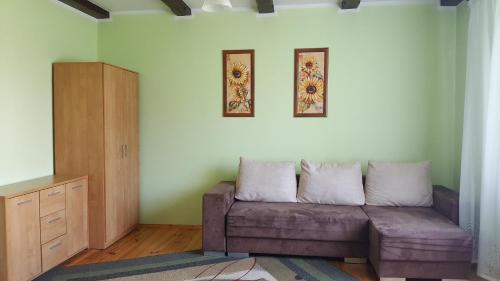 salon z kanapą i 2 zdjęciami na ścianie w obiekcie Dom z kominkiem dla 12os. w Kruklankach