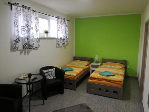 a bedroom with two beds and a chair and a table at Restaurace - penzion Bavorský dvůr in Sezemice