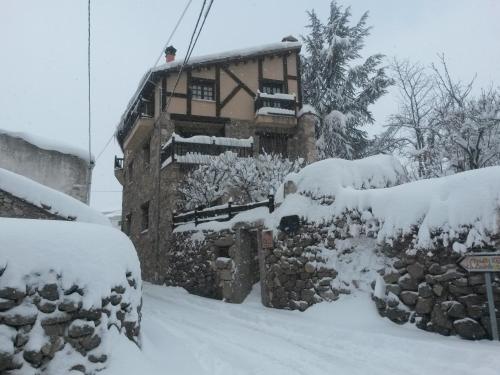 a house covered in snow in front at Artesano II in Navarredonda de Gredos