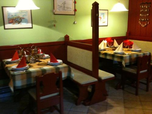 un comedor con dos mesas con sombreros rojos. en Motelnet.T, en Mosonmagyaróvár