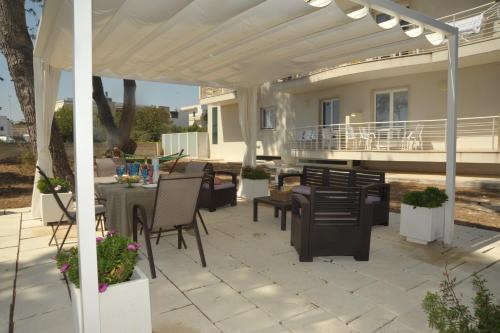 a patio with a table and chairs under a white pergola at MARIMAR - Apartments OTRANTO in Otranto