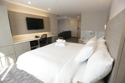 a hotel room with a white bed and a television at Days Inn by Wyndham Calgary North Balzac in Balzac